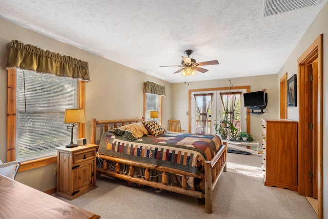 bedroom featuring ceiling fan, light colored carpet, access to exterior, and a textured ceiling