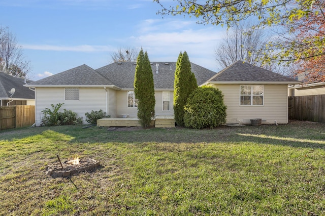 rear view of house with a deck, a lawn, and an outdoor fire pit