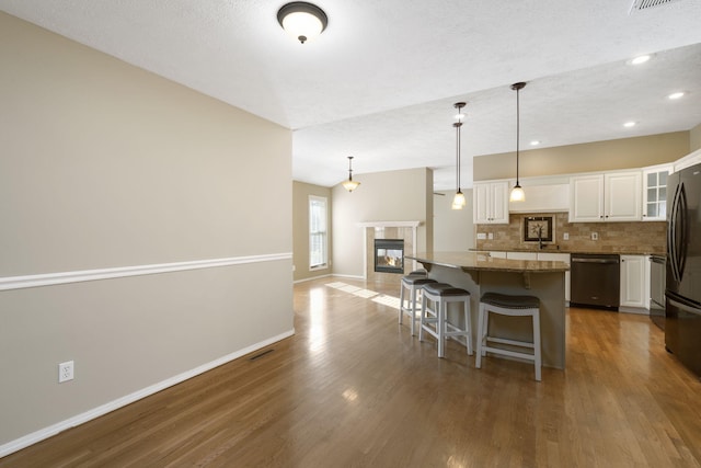 kitchen featuring white cabinets, hardwood / wood-style flooring, hanging light fixtures, and dishwasher