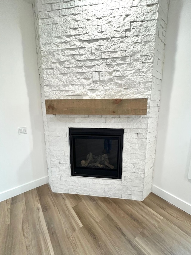 interior details featuring a stone fireplace and wood-type flooring