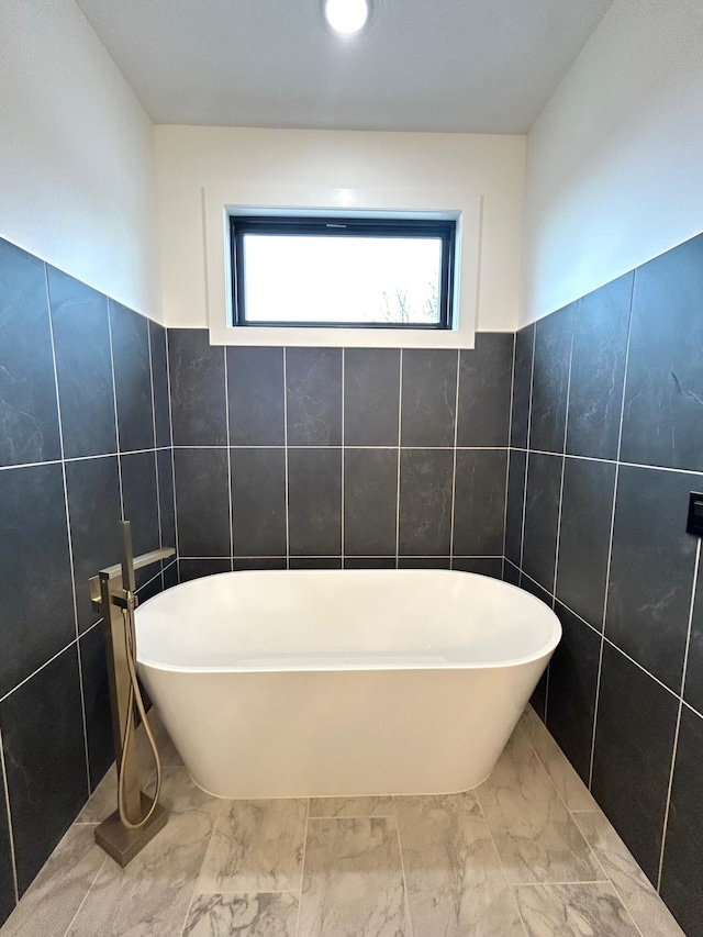 bathroom featuring a washtub and tile walls