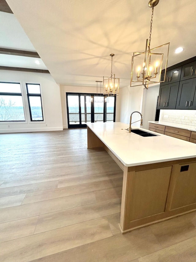 kitchen featuring a healthy amount of sunlight, sink, an island with sink, and pendant lighting