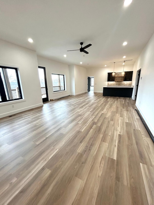 unfurnished living room featuring ceiling fan and light hardwood / wood-style flooring