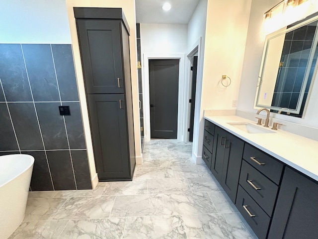 bathroom with a bathing tub, vanity, and tile walls