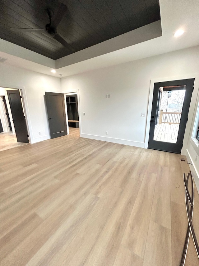 interior space featuring ceiling fan, light hardwood / wood-style flooring, and a tray ceiling