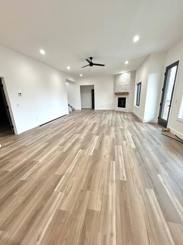 unfurnished living room featuring ceiling fan, a fireplace, and light hardwood / wood-style flooring