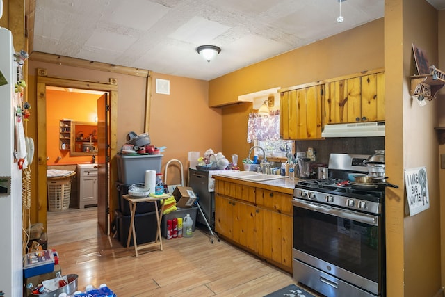 kitchen with sink, decorative backsplash, stainless steel range with gas stovetop, and light wood-type flooring