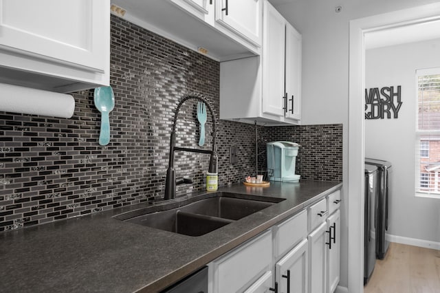 kitchen featuring sink, backsplash, white cabinetry, light hardwood / wood-style flooring, and independent washer and dryer