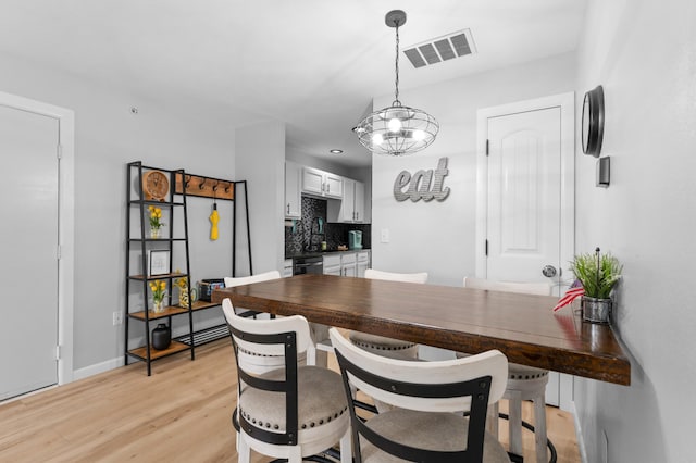 dining area featuring light hardwood / wood-style floors, sink, and a chandelier