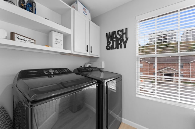 washroom featuring cabinets, a wealth of natural light, and washer and dryer