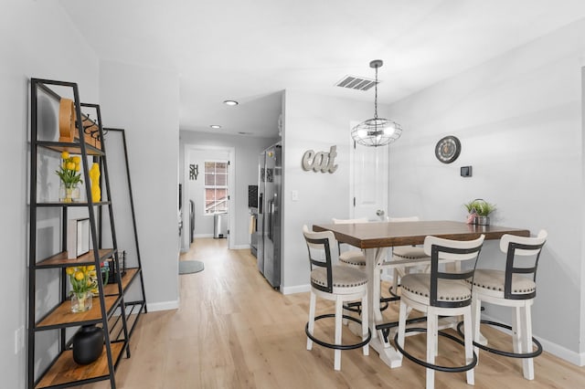 kitchen featuring light hardwood / wood-style floors, a notable chandelier, decorative light fixtures, and stainless steel fridge with ice dispenser