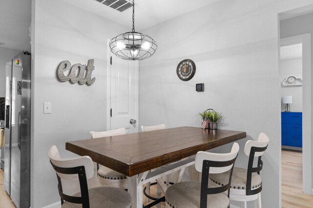 dining area with light hardwood / wood-style floors and an inviting chandelier