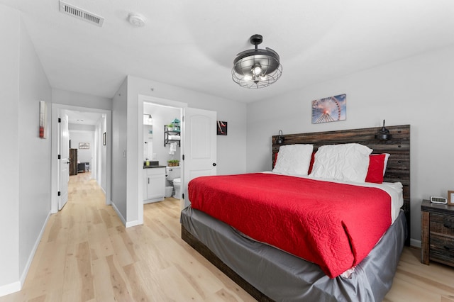 bedroom with light hardwood / wood-style floors and connected bathroom