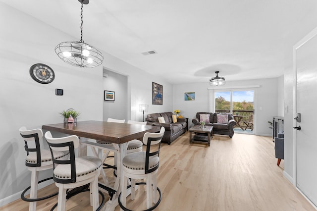 dining space featuring light wood-type flooring and an inviting chandelier