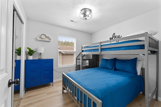 bedroom with a textured ceiling and light hardwood / wood-style floors