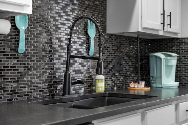 kitchen featuring backsplash, sink, and white cabinets