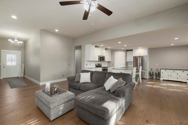 living room featuring dark hardwood / wood-style flooring, sink, and ceiling fan with notable chandelier