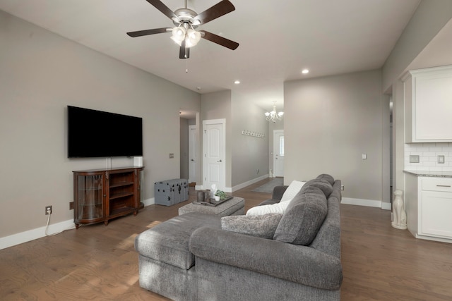 living room featuring ceiling fan with notable chandelier and dark hardwood / wood-style flooring