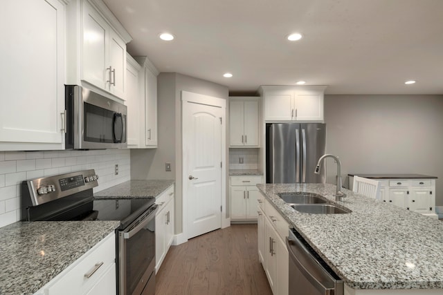 kitchen featuring stainless steel appliances, an island with sink, sink, and white cabinetry