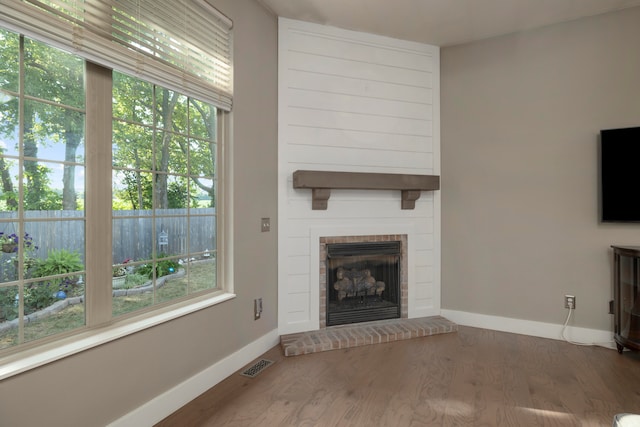 unfurnished living room with a brick fireplace and wood-type flooring