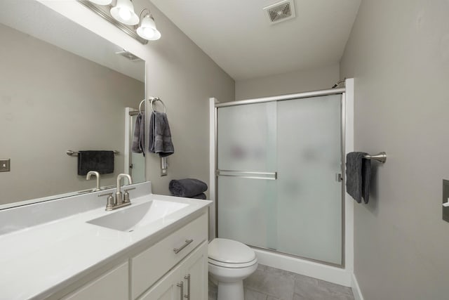 bathroom with vanity, toilet, tile patterned flooring, and a shower with door