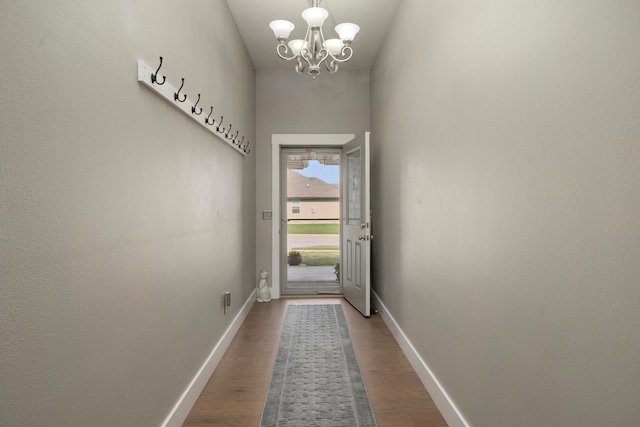 doorway with hardwood / wood-style floors and a notable chandelier