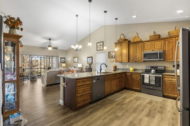 kitchen with pendant lighting, lofted ceiling, ceiling fan with notable chandelier, kitchen peninsula, and stainless steel appliances