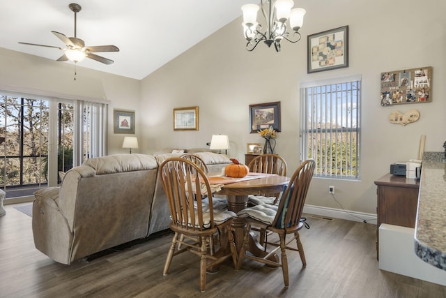 dining space featuring dark hardwood / wood-style flooring, high vaulted ceiling, a healthy amount of sunlight, and ceiling fan with notable chandelier