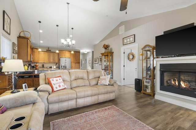 living room featuring ceiling fan with notable chandelier, high vaulted ceiling, dark wood-type flooring, and sink