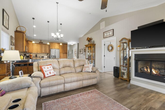 311 Cedar Glade Dr, Branson West, MO 65737 - living area featuring ceiling fan, wood finished floors, a chandelier, high vaulted ceiling, and a lit fireplace