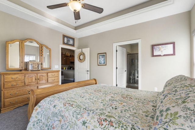 bedroom with ceiling fan, a raised ceiling, carpet floors, and connected bathroom