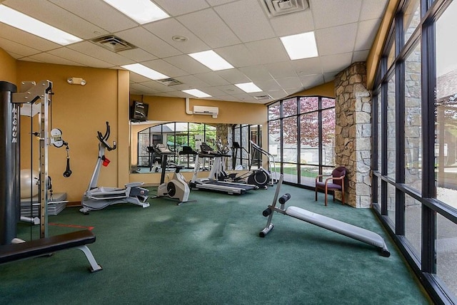 exercise room featuring a drop ceiling, carpet floors, and a wall mounted air conditioner