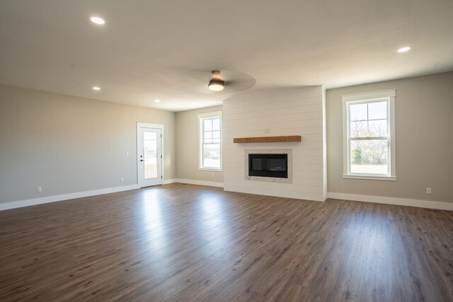 unfurnished living room with dark wood-type flooring, a fireplace, and ceiling fan