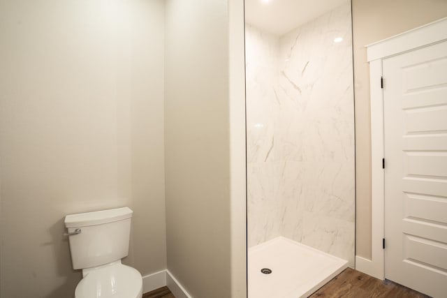 bathroom with hardwood / wood-style floors, toilet, and a shower