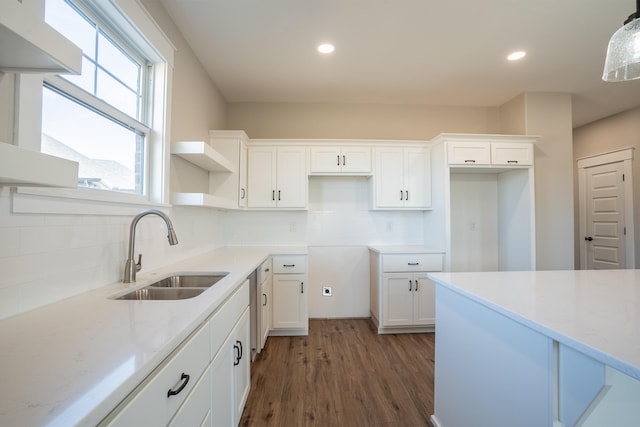 kitchen with tasteful backsplash, white cabinetry, pendant lighting, sink, and dark wood-type flooring