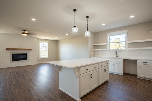 kitchen featuring white cabinets, sink, dark hardwood / wood-style floors, a kitchen island, and pendant lighting