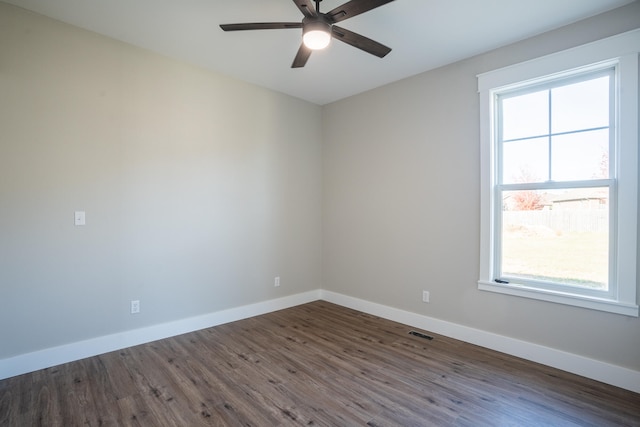 empty room featuring ceiling fan, a wealth of natural light, and dark hardwood / wood-style floors