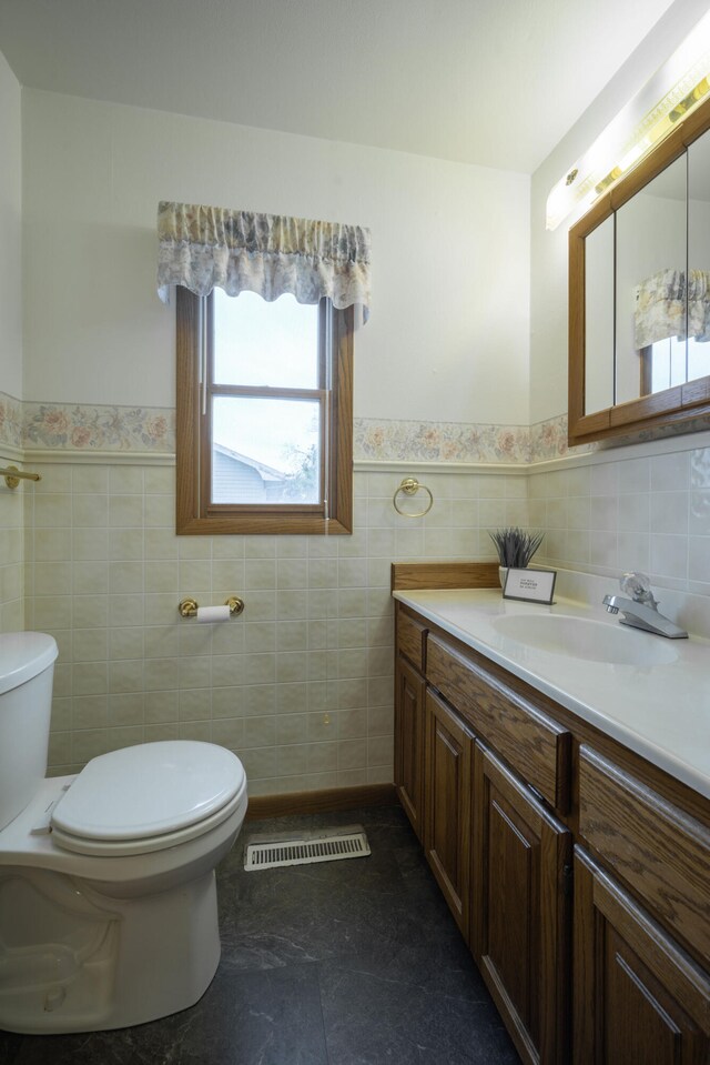 bathroom with vanity, tile walls, and toilet