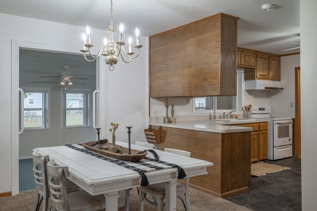 kitchen featuring kitchen peninsula, ceiling fan with notable chandelier, sink, electric range, and decorative light fixtures