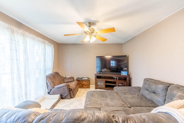 living room with a textured ceiling, light colored carpet, and ceiling fan