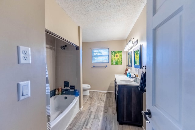 full bathroom with vanity, a textured ceiling, tiled shower / bath combo, hardwood / wood-style floors, and toilet