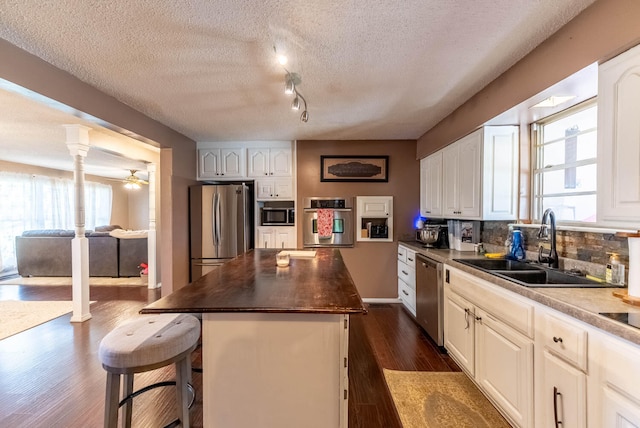 kitchen featuring stainless steel appliances, a kitchen island, a wealth of natural light, and dark wood-type flooring