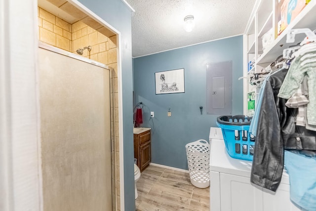 bathroom featuring electric panel, toilet, a textured ceiling, an enclosed shower, and wood-type flooring