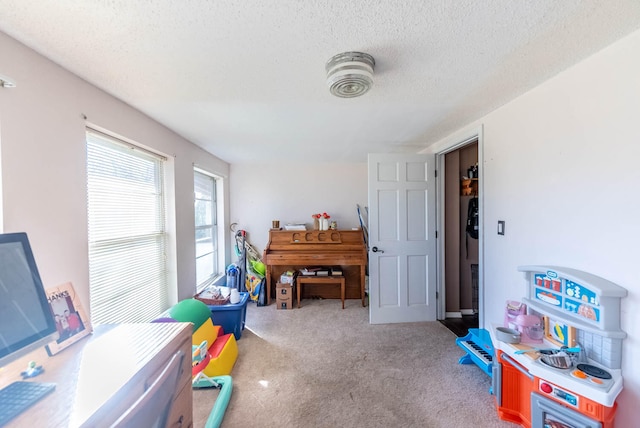 playroom featuring a textured ceiling and light colored carpet