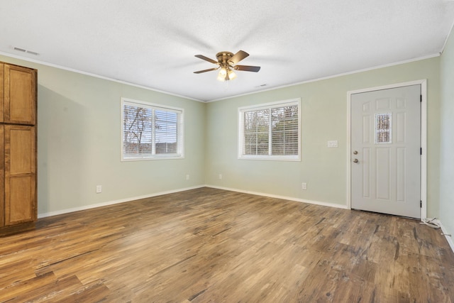 entrance foyer with wood-type flooring, a textured ceiling, ceiling fan, and crown molding