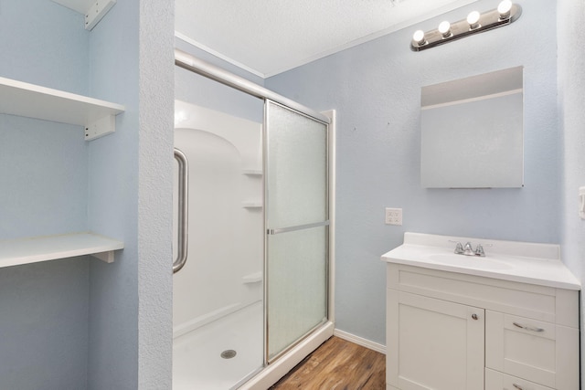 bathroom featuring a textured ceiling, vanity, wood-type flooring, and a shower with shower door