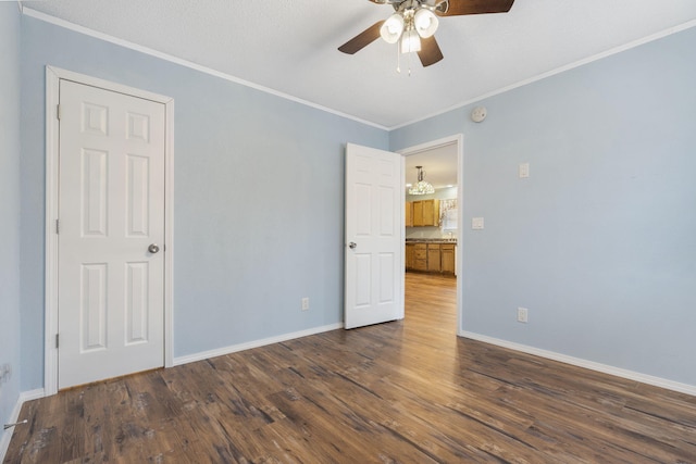 spare room with a textured ceiling, crown molding, ceiling fan, and dark wood-type flooring