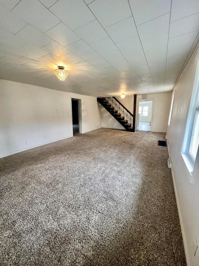 carpeted empty room featuring stairway and a healthy amount of sunlight