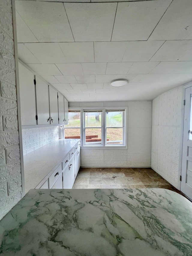 kitchen featuring white cabinetry and brick wall