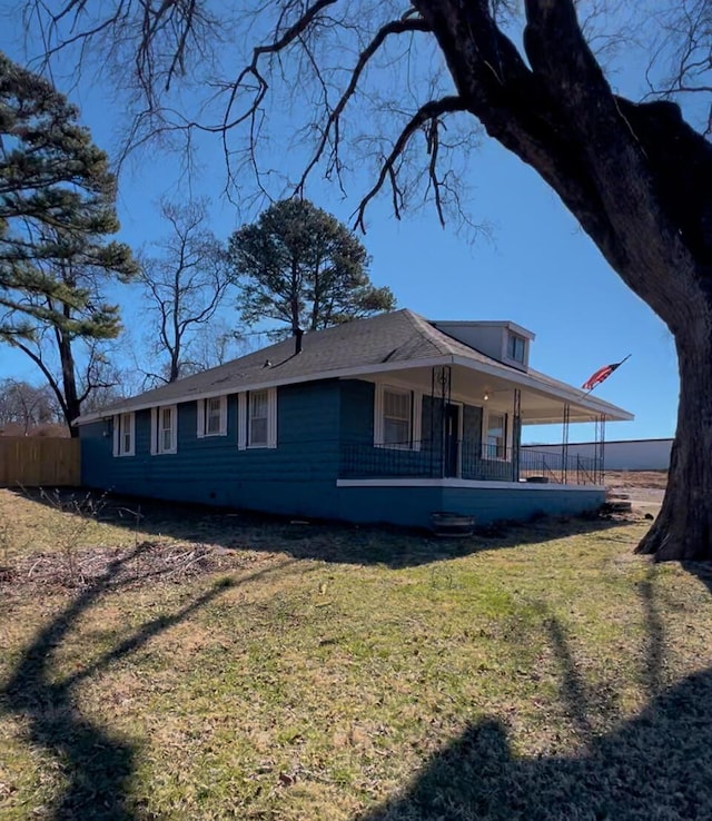 view of side of home with covered porch and a yard